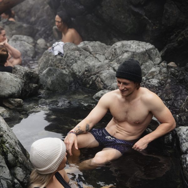 A group of people sitting on the rocks in Hot Springs Cove, Tofino, BC Canada