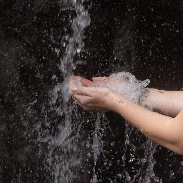 A woman standing next to a waterfall in Hot Springs Cove, Tofino, BC Canada