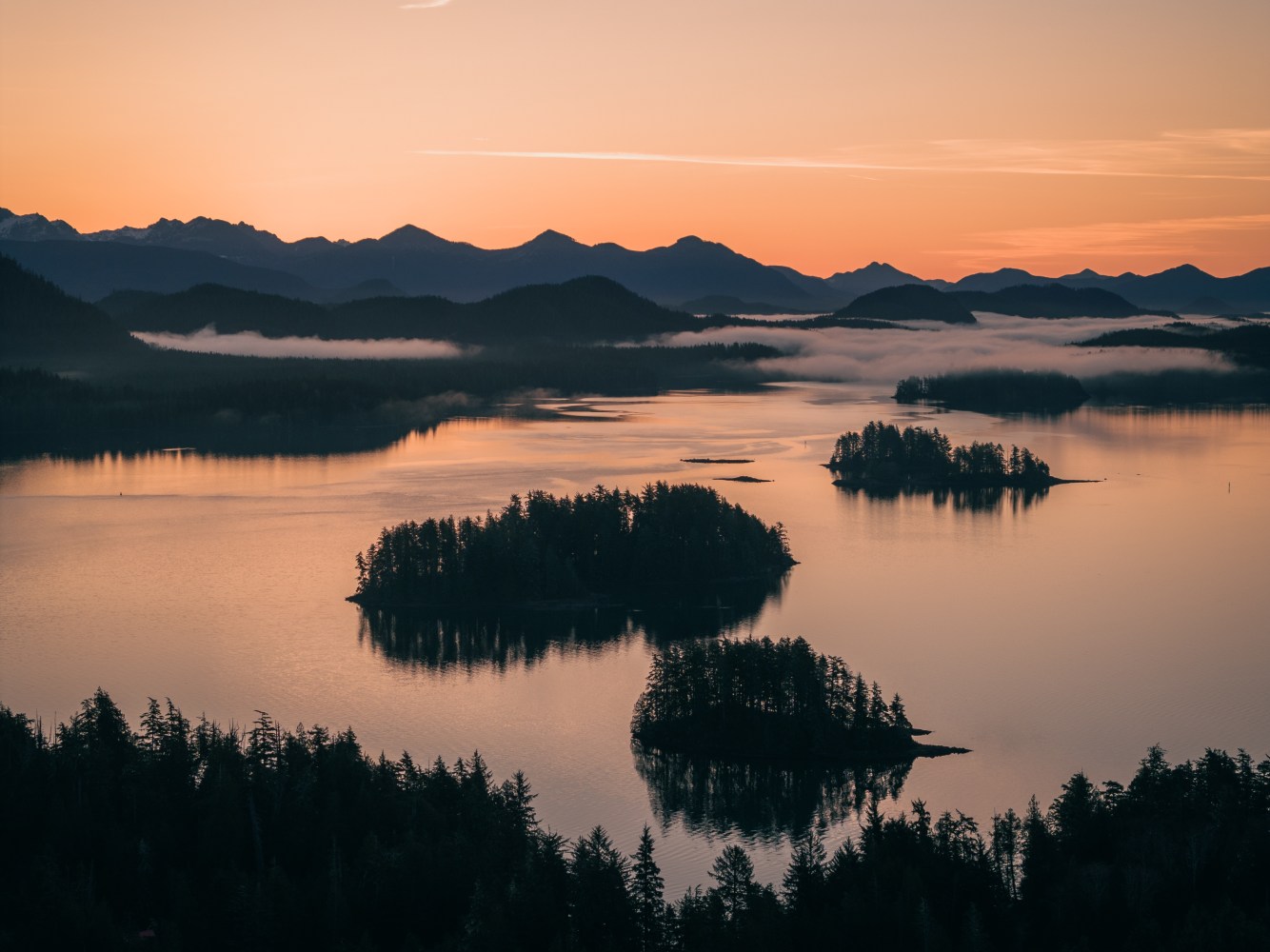 a sunset over a body of water with a mountain in the background