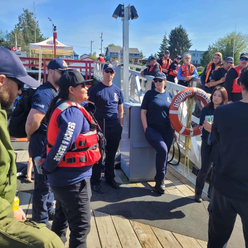People in uniforms and life vests gather on a dock for a briefing.