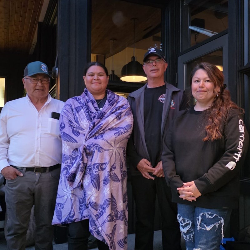 Four people standing in front of a building, wearing casual clothes.